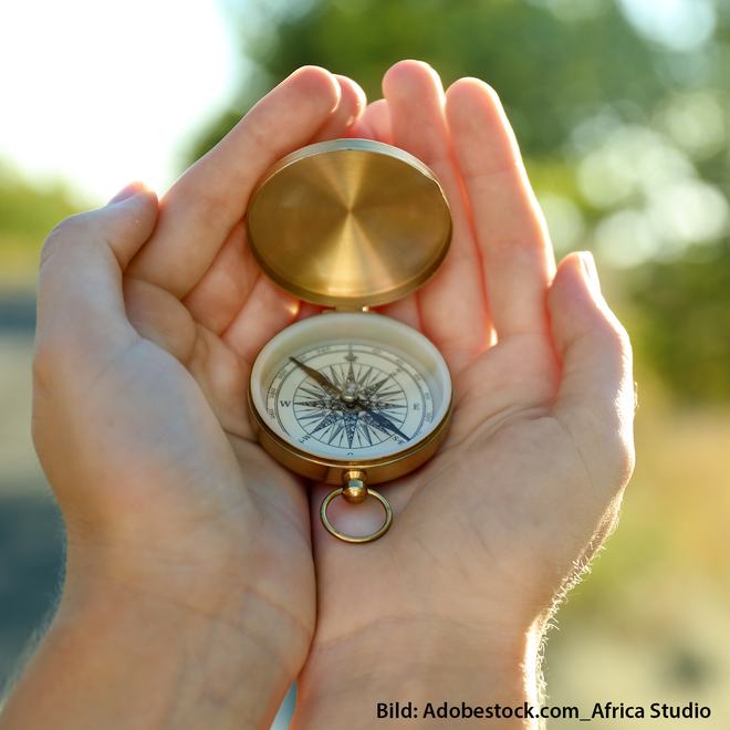 zwei Hände halten einen geöffneten Taschenkompass