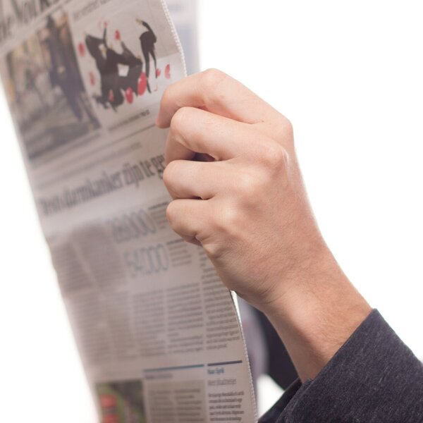 zwei Hände halten eine geöffnete Zeitung zum Lesen